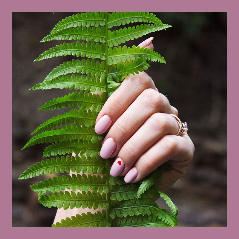 Różowy manicure hybrydowy z czerownym serduszkiem na paznocku palca serdecznego.